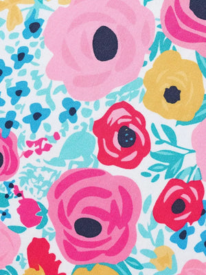 Fabric with a white background and a vibrant floral print featuring pink, red, yellow, and blue flowers.