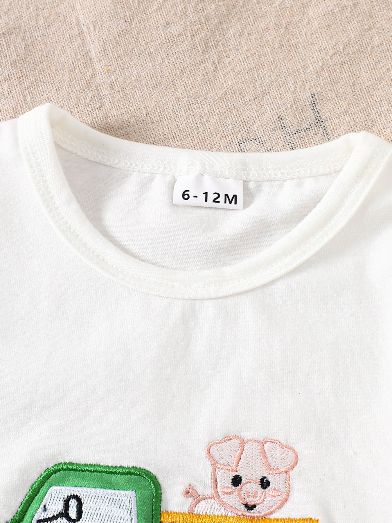 White cotton baby tee with embroidered tractor and pig detail, crew neck.
