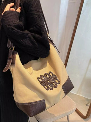 Khaki canvas tote bag with brown leather trim and embroidered logo detail