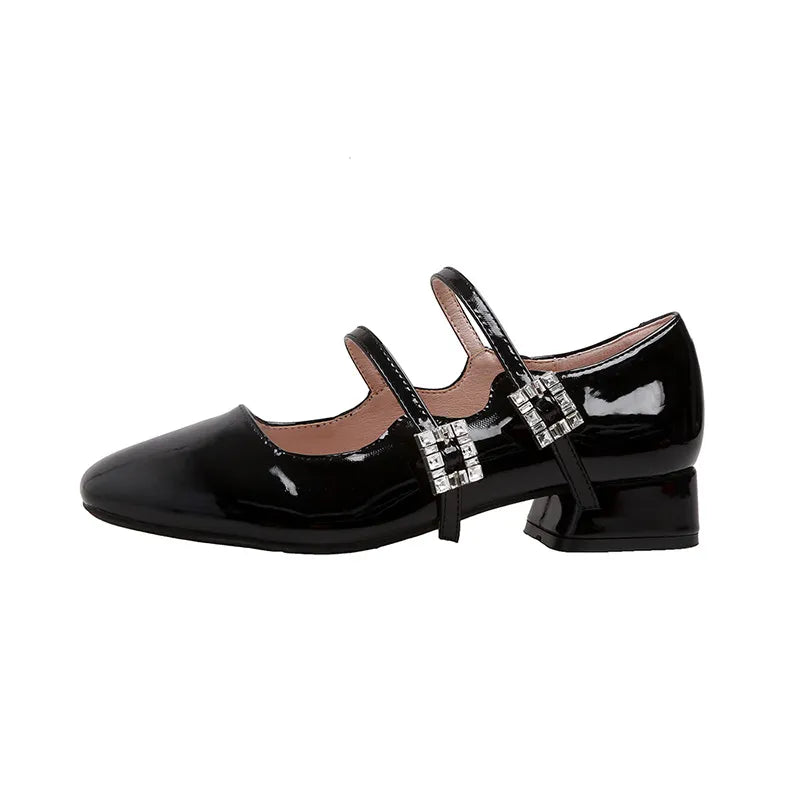 Black patent leather double strap Mary Janes with rhinestone buckles.