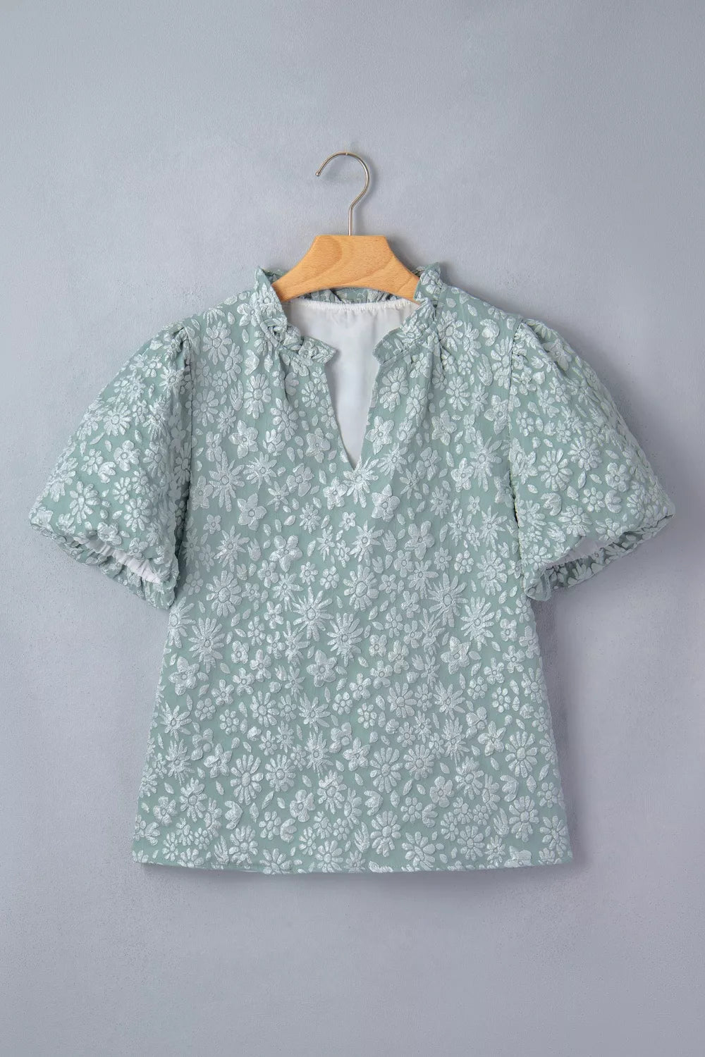 Embroidered puff sleeve floral shirt in light green polyester with ruffled neckline and V-neck.