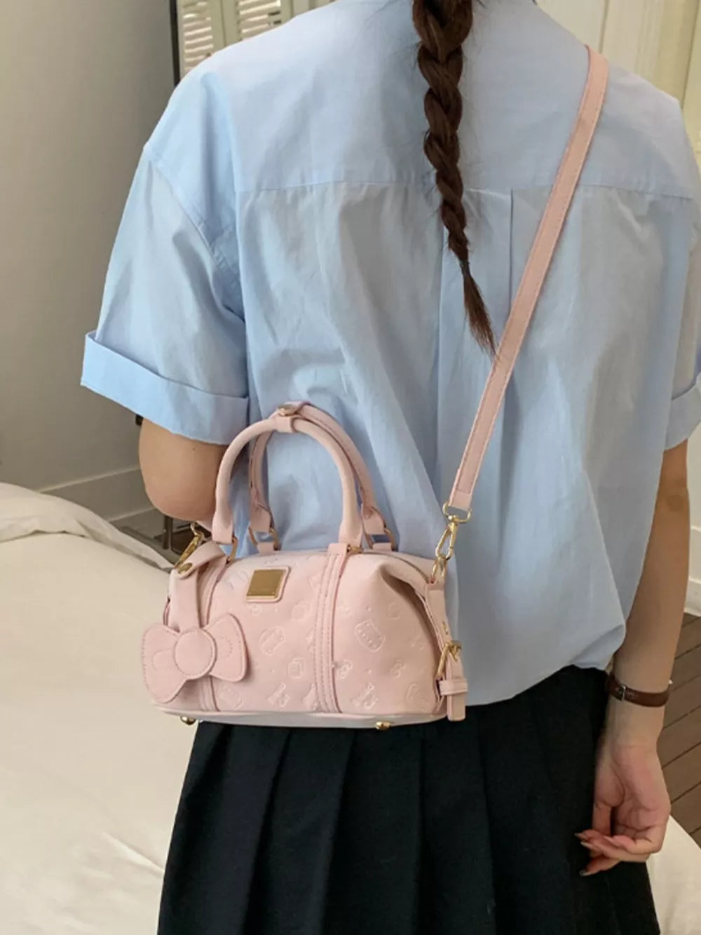 Charming mini crossbody bag in blush pink with bow detail and embossed pattern.
