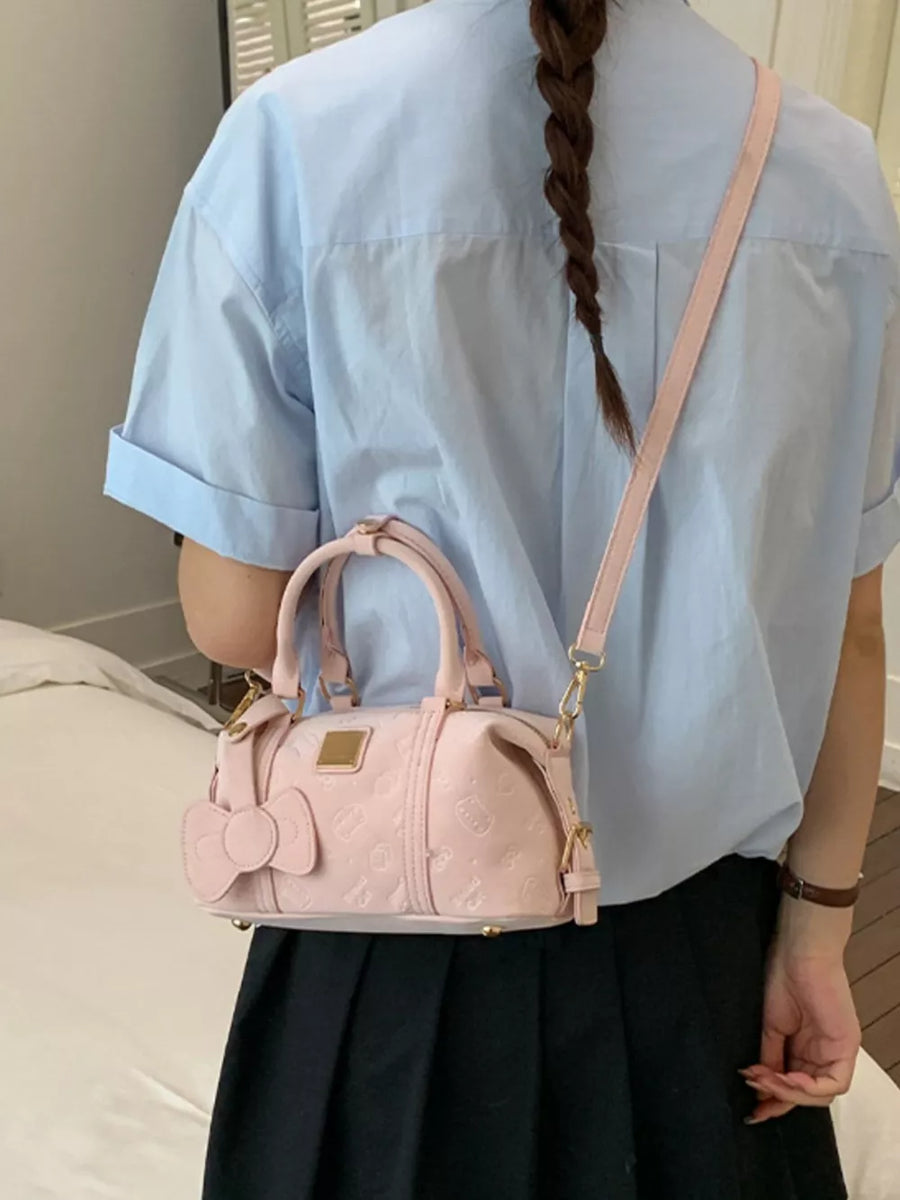 Charming mini crossbody bag in blush pink with bow detail and embossed pattern.