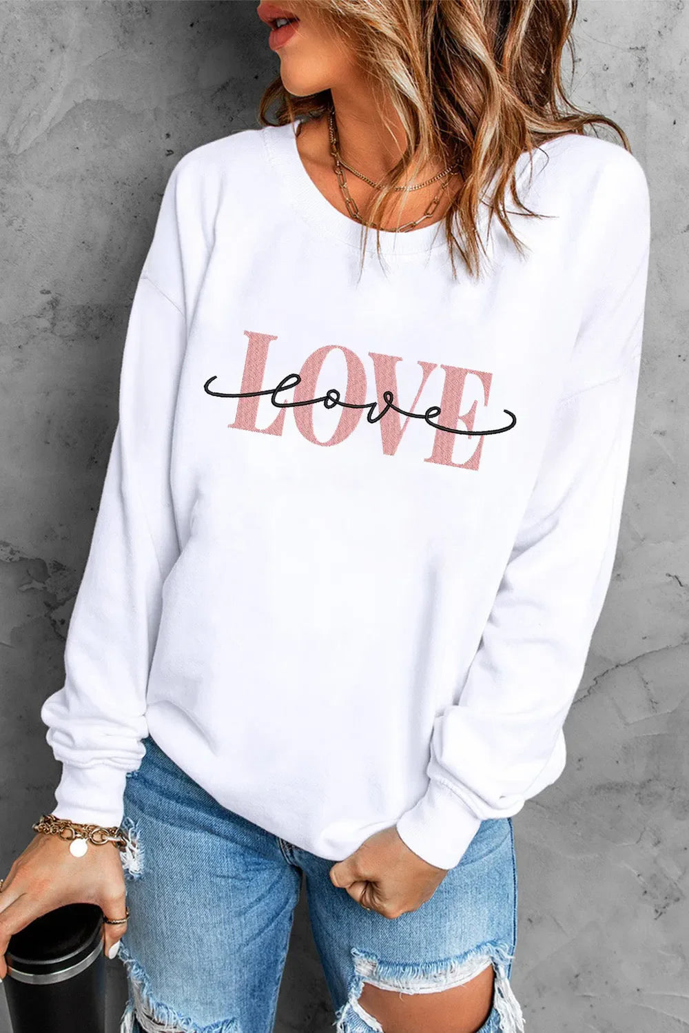 White crewneck sweatshirt with pink and black "Love" script graphic.