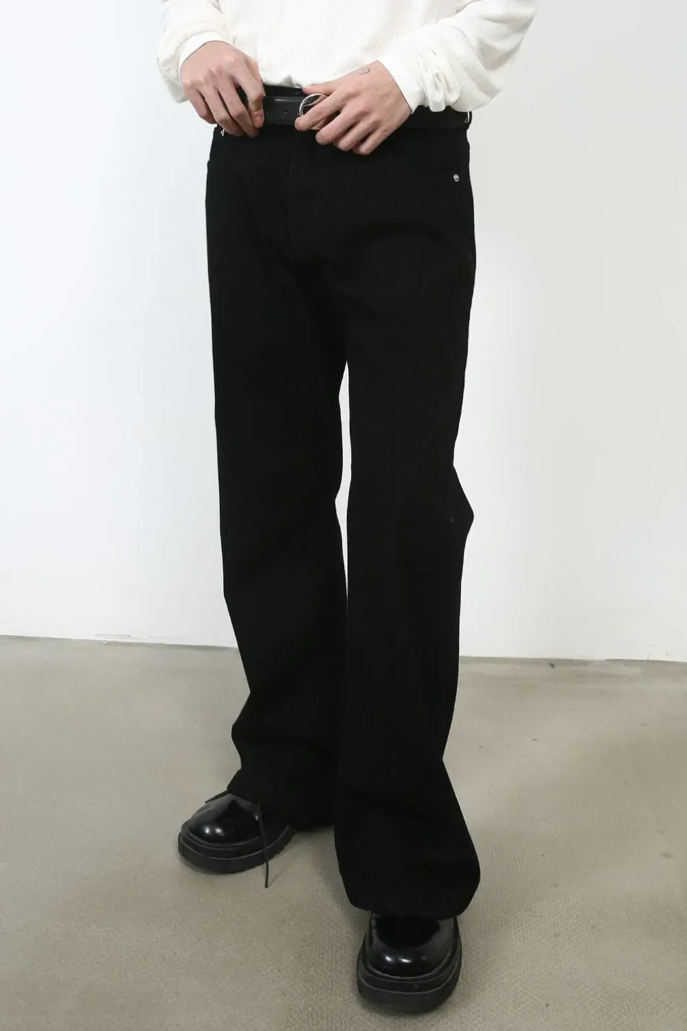 Black bootcut jeans with a casual fit, styled with a belt and chunky shoes.