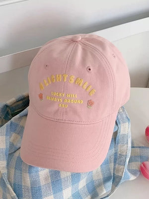 Pink baseball cap with yellow embroidered text and floral details.