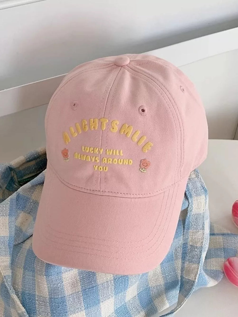 Pink baseball cap with yellow embroidered text and floral details.