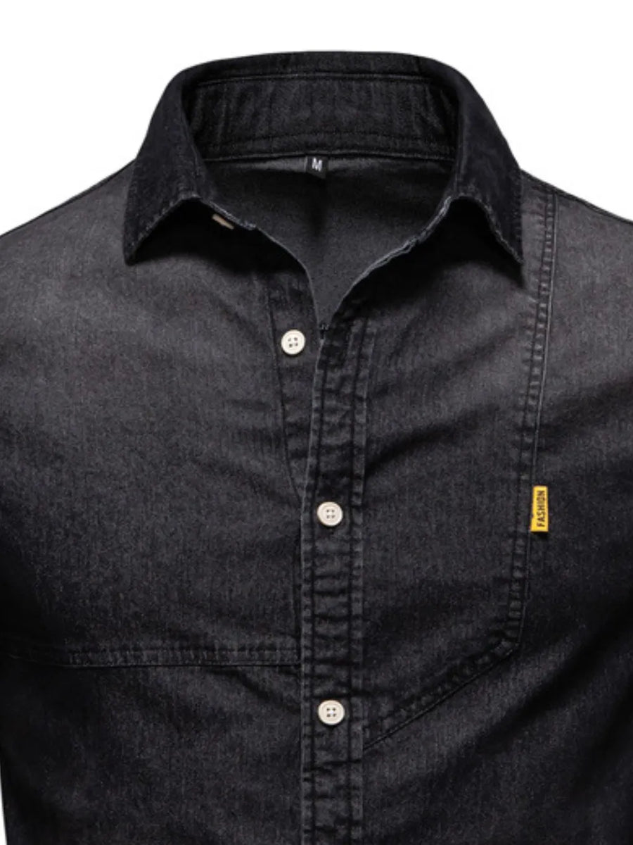 Dark wash denim shirt with asymmetric pocket detail and button-down front.