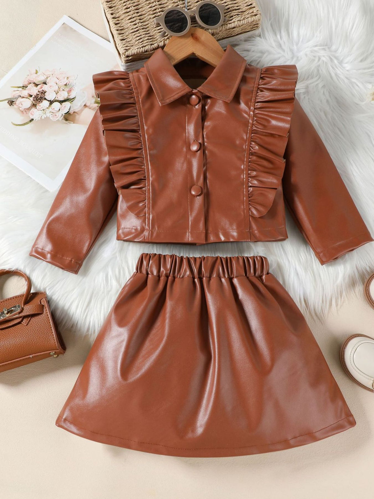 Brown faux leather toddler set with ruffled collared jacket and elastic waist skirt.