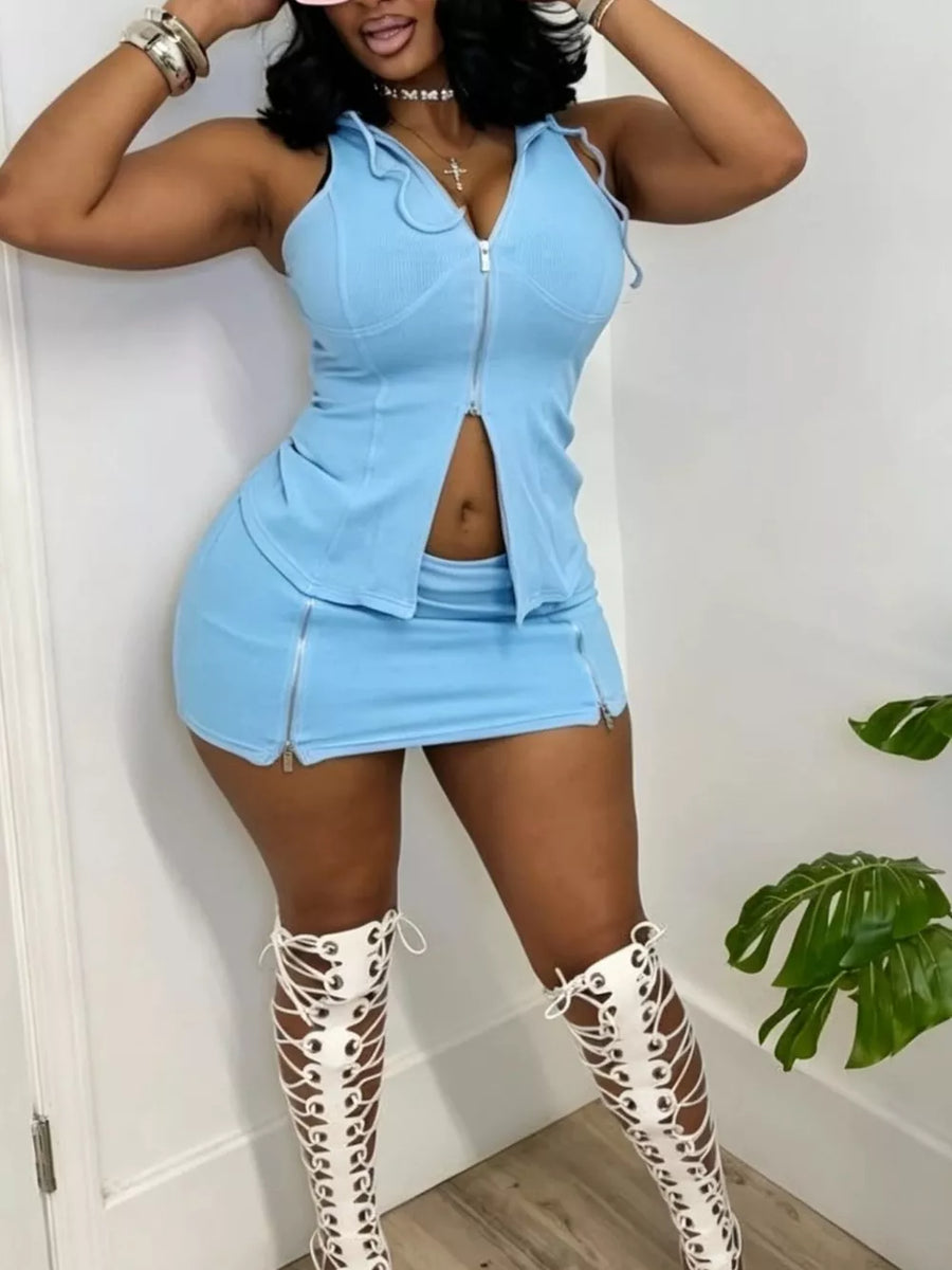 Blue hooded zippered two-piece set with skirt and zipper details, styled with lace-up boots.