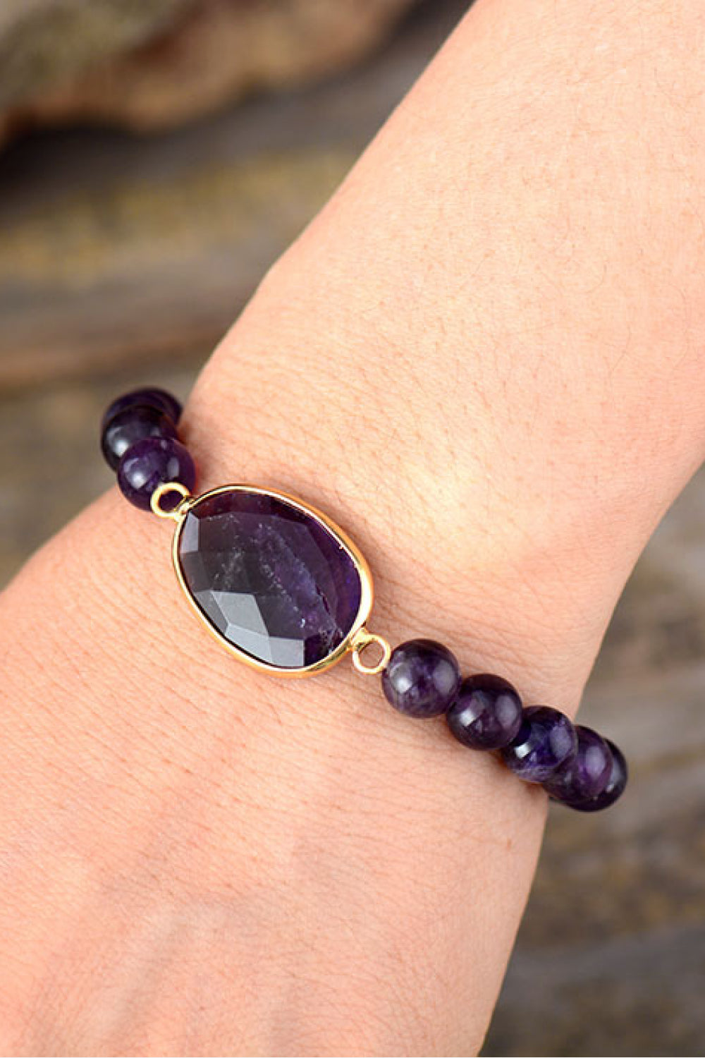 Amethyst beaded bracelet with faceted oval stone and gold-tone setting.