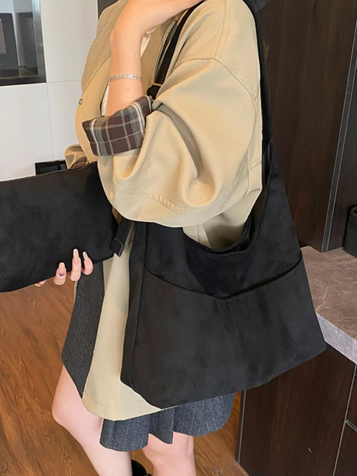 Large black suede shoulder bag with front pockets and adjustable strap.