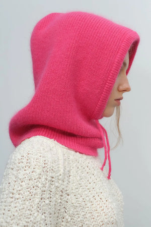Hot pink knit balaclava with drawstring hood, worn over a white sweater.