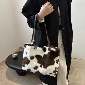 Cowhide print faux fur shopper bag with brown and white pattern and leather straps.
