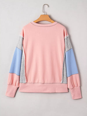 Oversized pink sweatshirt with contrast color block sleeves in blue and grey, featuring contrast stitching.
