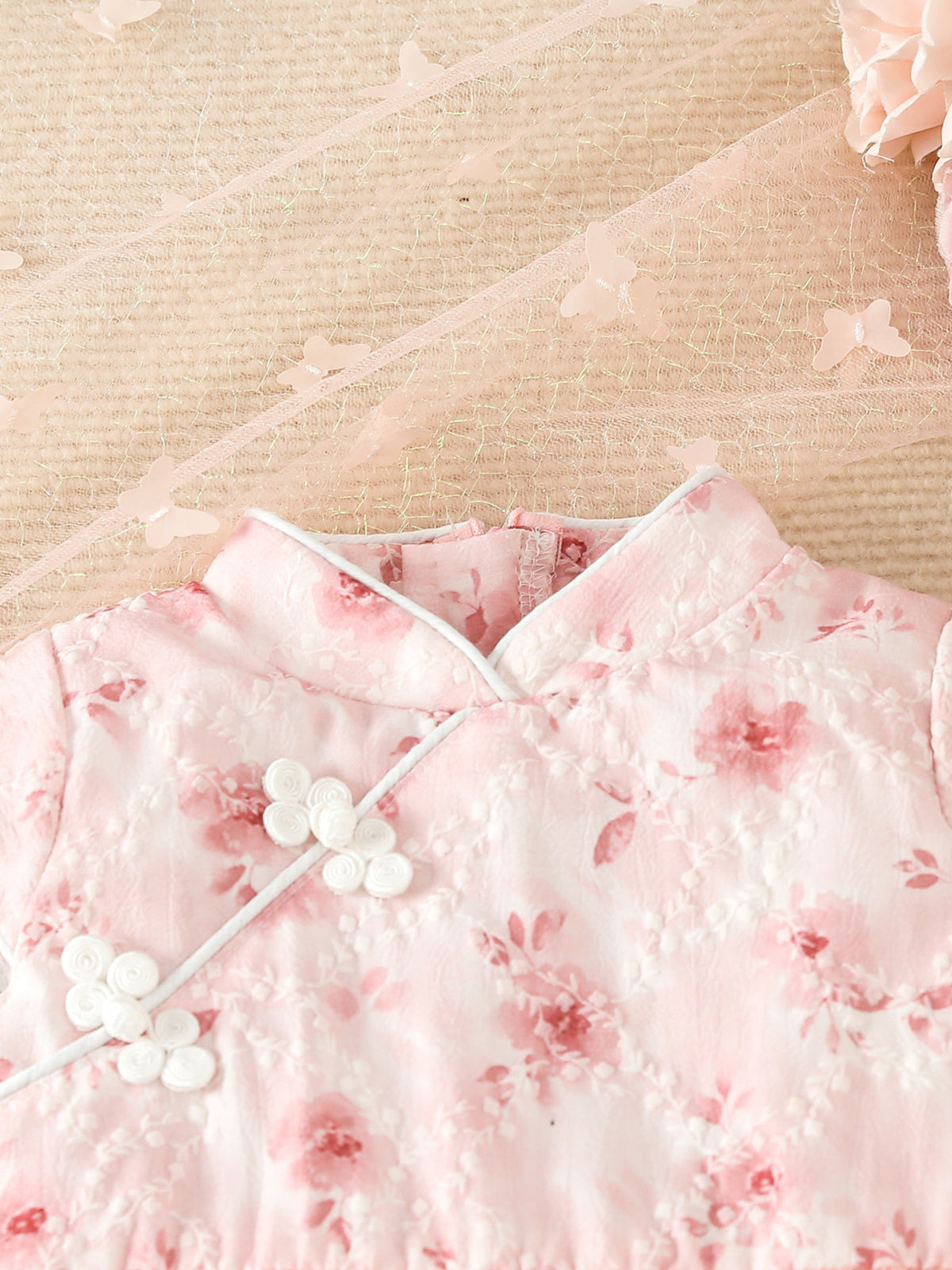 Pink floral cap sleeve baby dress with white frog buttons and butterfly trim.