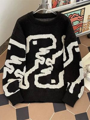 Black oversized sweater with abstract white graphic pattern and ribbed hem.