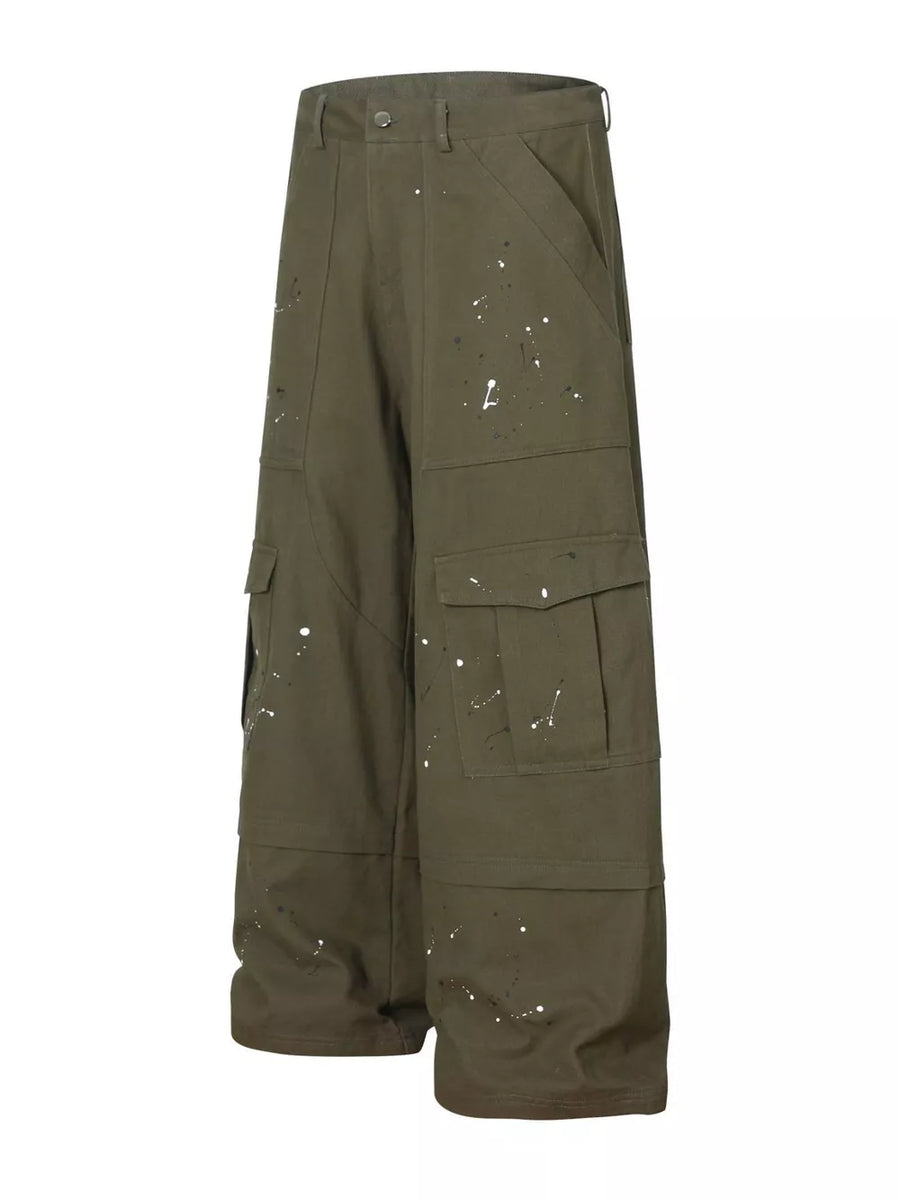Olive green cotton cargo pants with white paint splatter design and button fly.