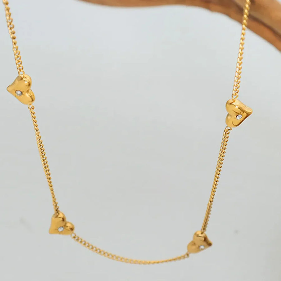 Gold chain necklace with small heart charms and cubic zirconia accents