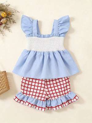 Baby blue ruffled top with smocked white bodice and red checkered shorts with ruffles.