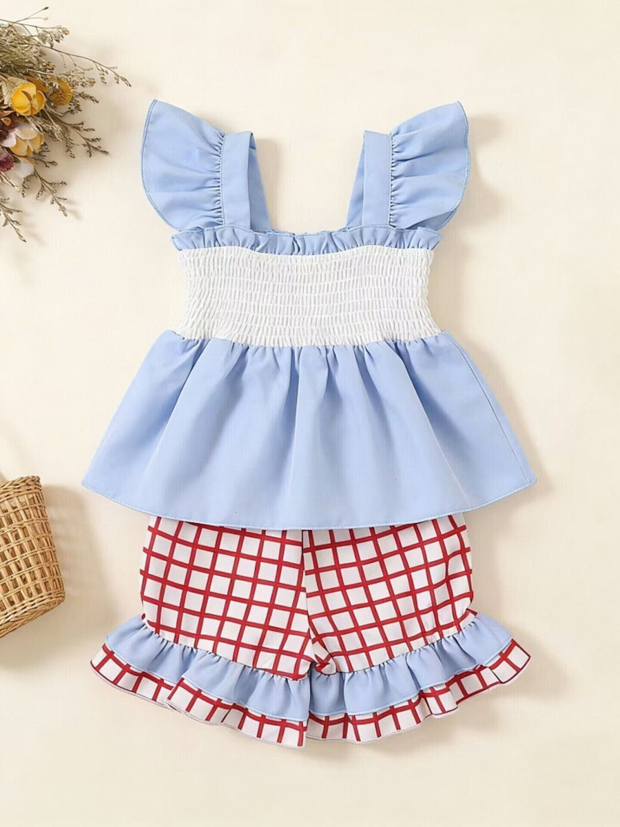 Baby blue ruffled top with smocked white bodice and red checkered shorts with ruffles.