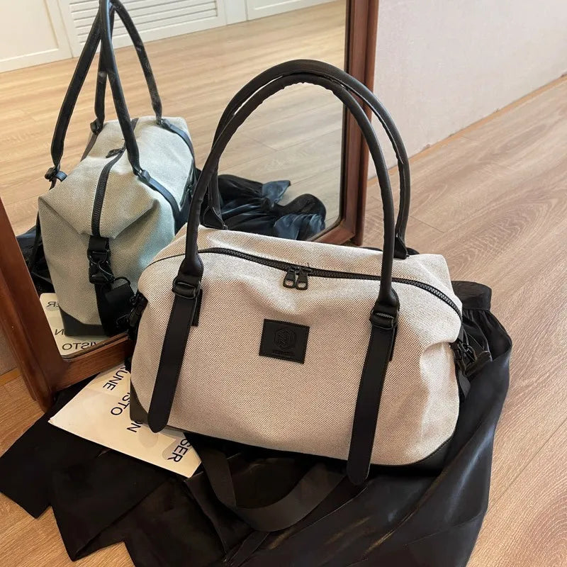 Canvas weekend holdall duffel bag in light beige with black leather handles and trim.