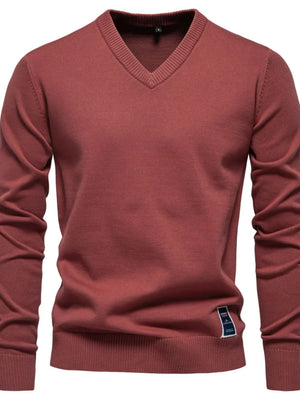 Rust V-neck ribbed knit sweater with a small blue and white logo tag on the hem.