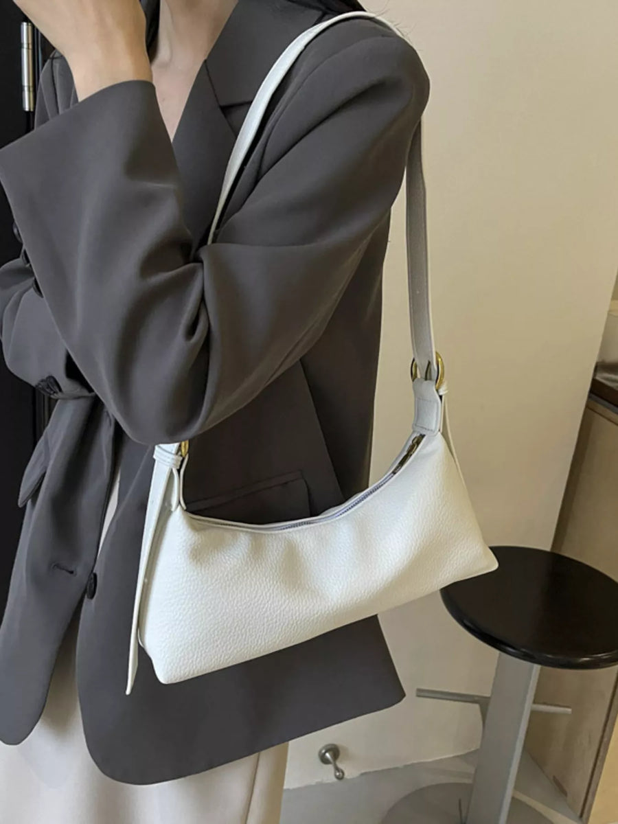 Minimalist white PU leather crossbody bag with adjustable strap and gold hardware detail.