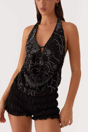 Black halter top with white floral embroidery and sequins, paired with ruched shorts.