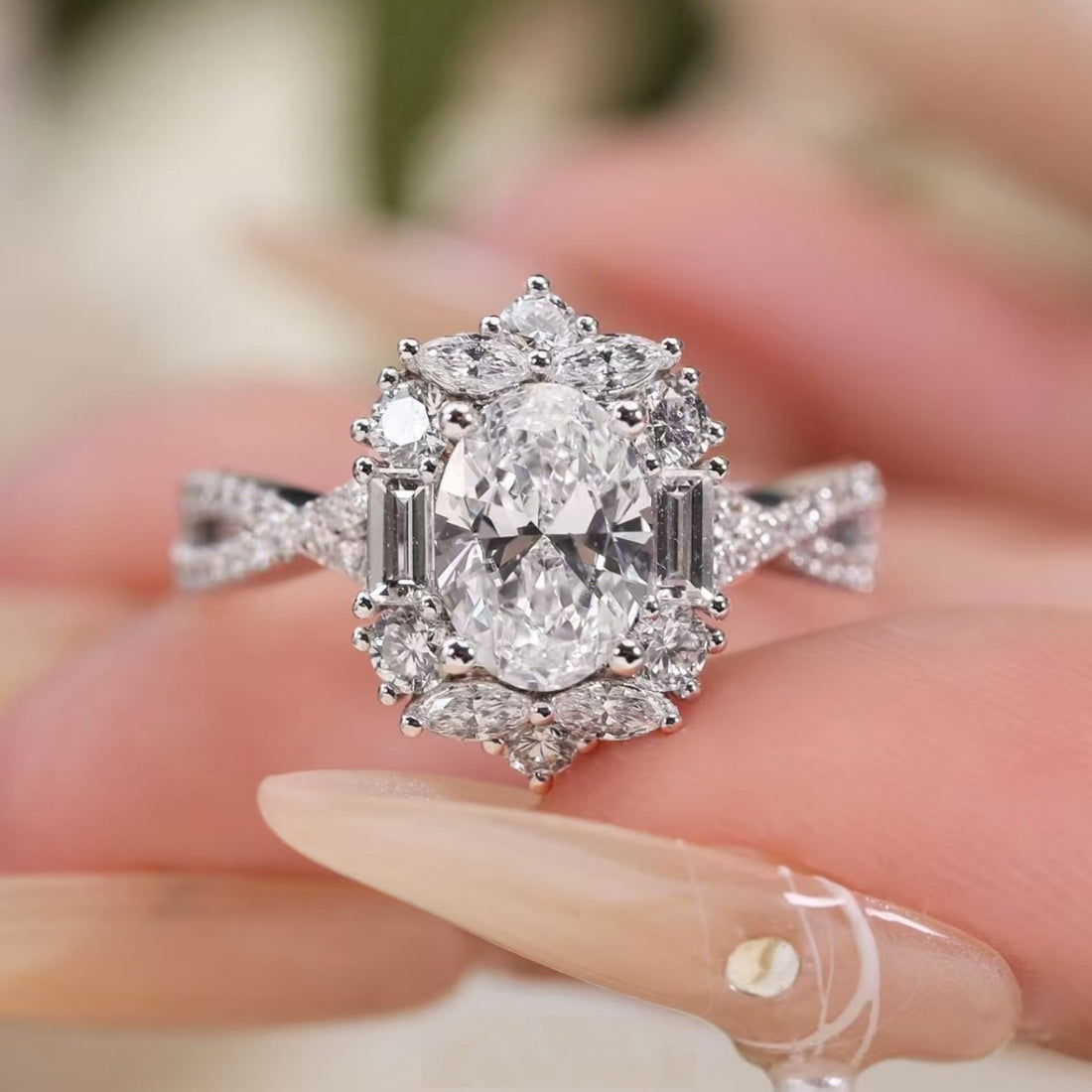 Sterling silver oval moissanite halo ring with twisted band and baguette accents.