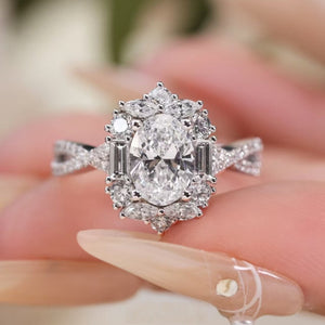 Sterling silver oval moissanite halo ring with twisted band and baguette accents.