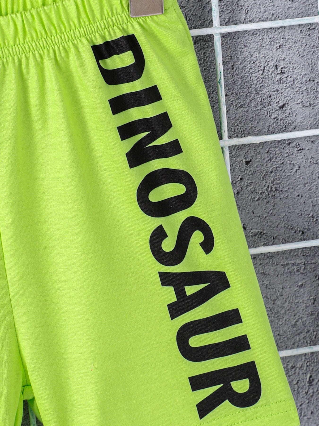 Neon green toddler shorts with black dinosaur text and elastic waistband.
