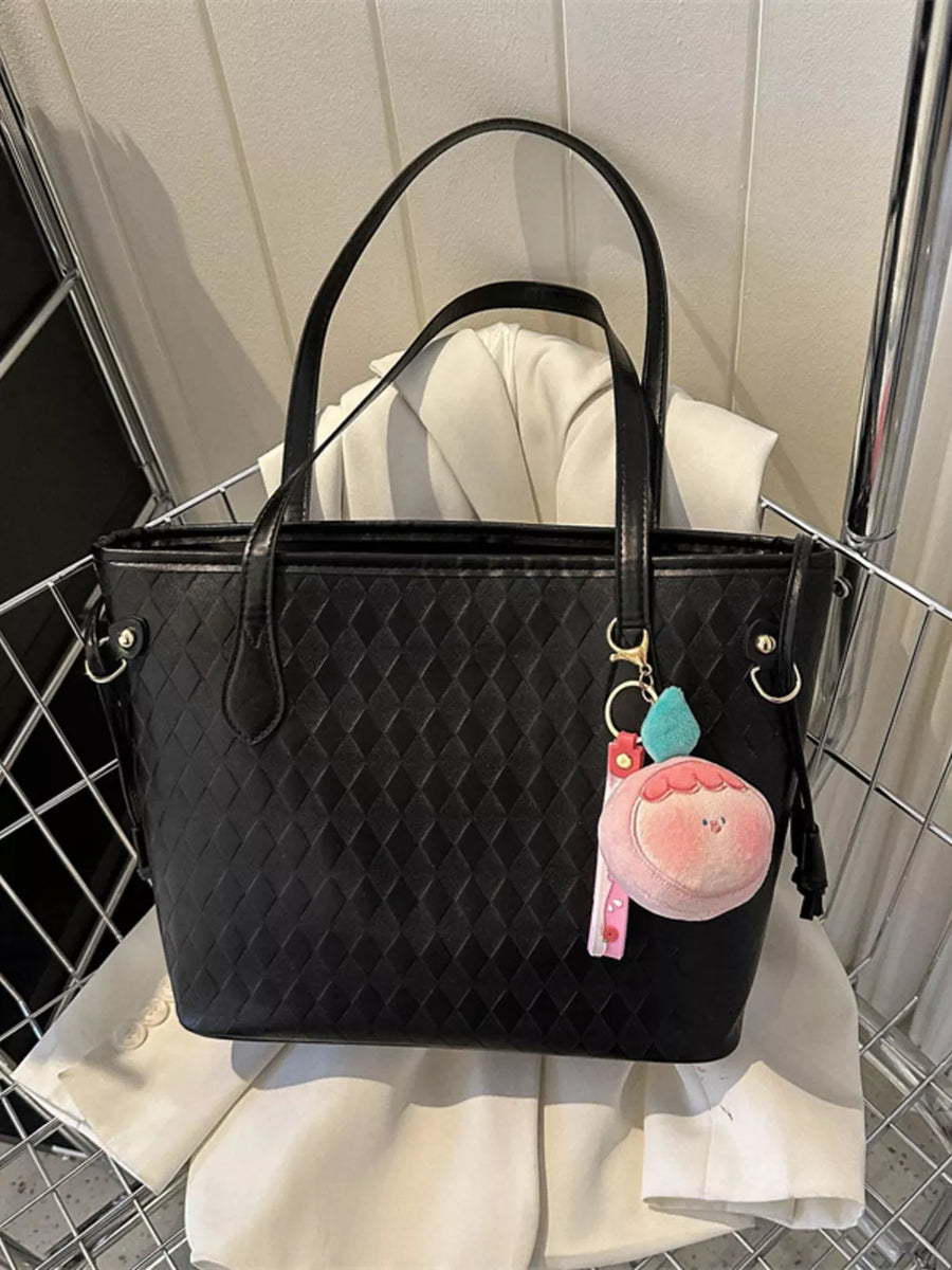 Black textured diamond woven tote bag with a cute peach charm and pink strap detail.