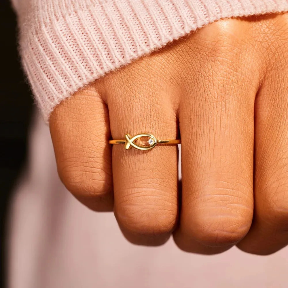 Gold ring with delicate fish motif and small zircon detail.