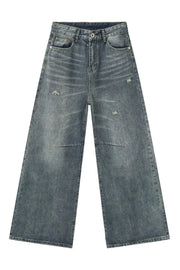 Oversized patchwork distressed denim trousers in medium wash with wide legs and raw hem.