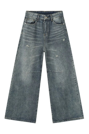 Oversized patchwork distressed denim trousers in medium wash with wide legs and raw hem.