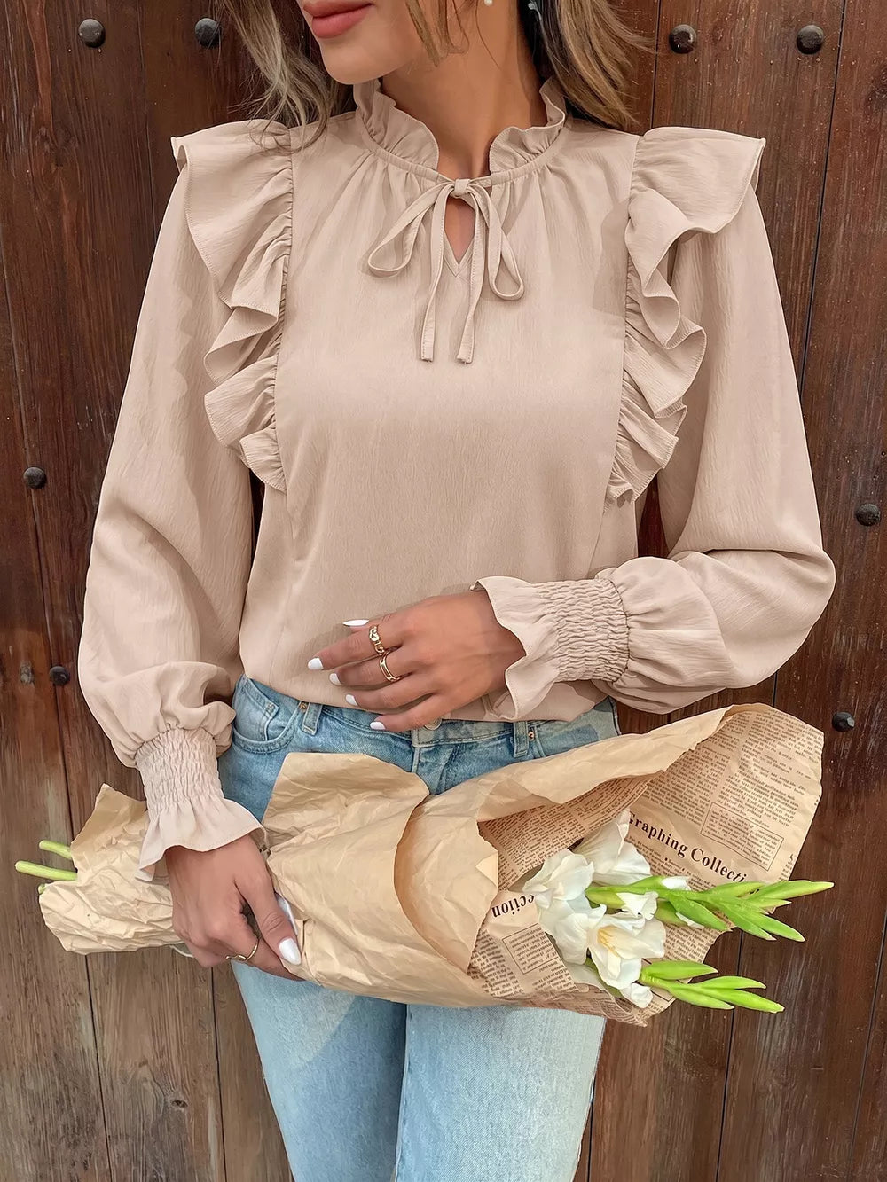 Chic beige long sleeve shirt with ruffled neckline and tie, smocked cuffs.