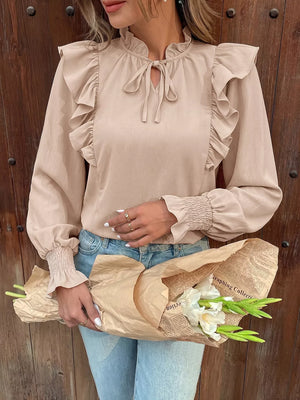 Chic beige long sleeve shirt with ruffled neckline and tie, smocked cuffs.