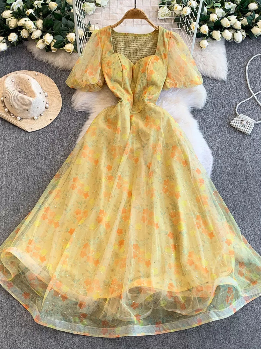 Yellow floral maxi dress with sweetheart neckline, puff sleeves, and glitter tulle overlay.