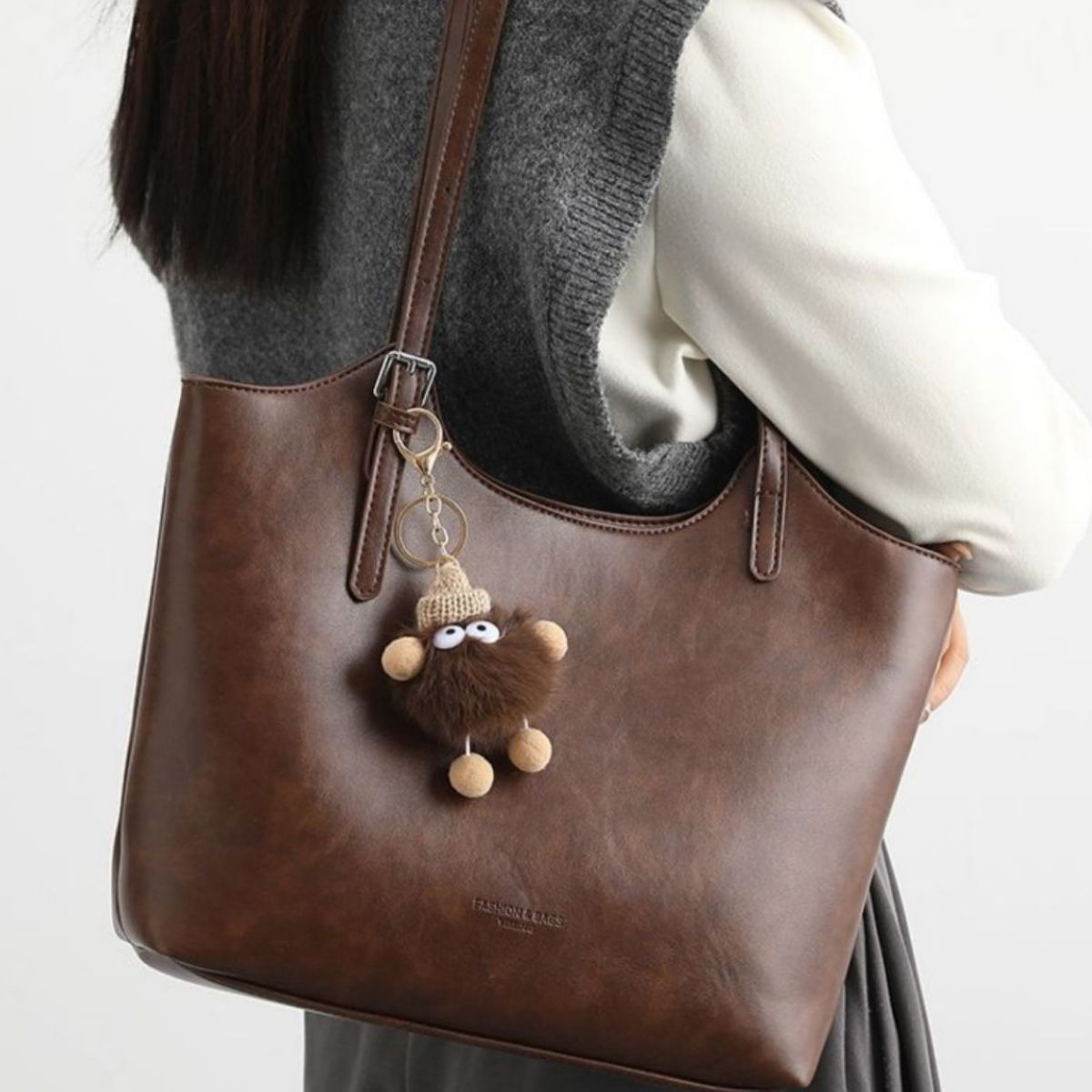 Brown pu leather tote bag with a fuzzy charm and adjustable strap