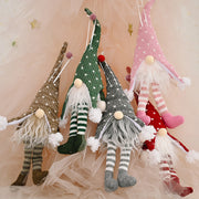 Knitted gnome ornaments in light gray, dark green, blush pink, and deep red with striped legs and fluffy beards.