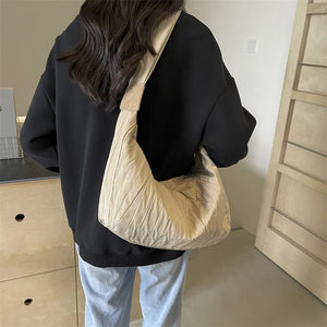 Beige quilted crescent shoulder bag with ruched detailing and a single strap.