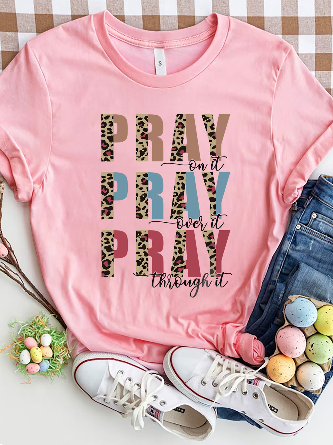 Textured graphic t-shirt in blush pink with "PRAY on it, PRAY over it, PRAY through it" text and leopard print accents.