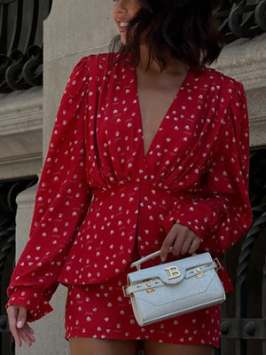Red printed mini dress with V-neck and long sleeves, styled with a white croc-embossed handbag.