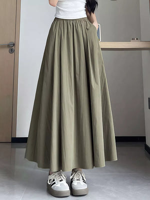 Maxi skirt in olive green with pockets and a gathered waist, styled with a white top and sneakers.