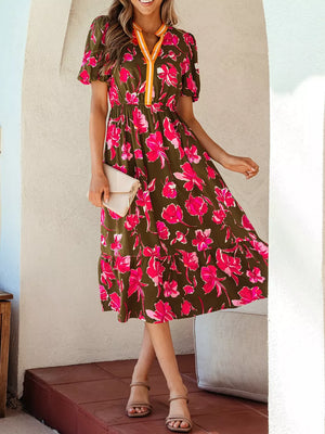 Print split neck dress with short sleeves, elastic waist, and tiered hem in olive green with pink floral print.