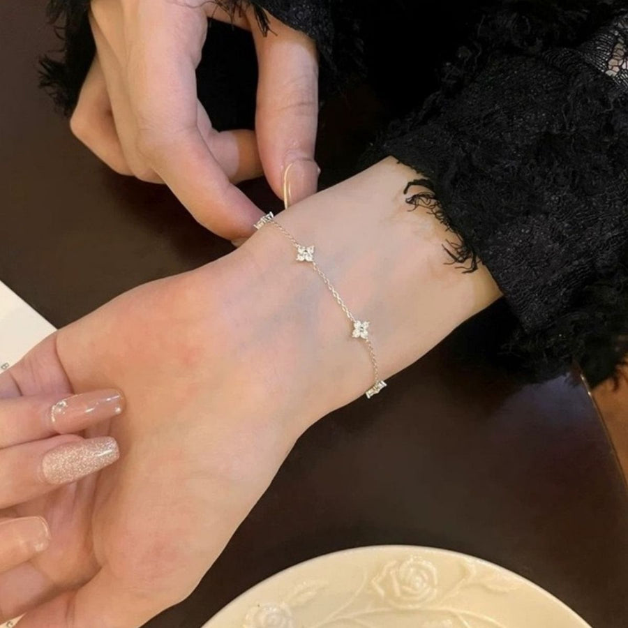 Delicate silver bracelet with four-leaf clover charms and crystal accents.