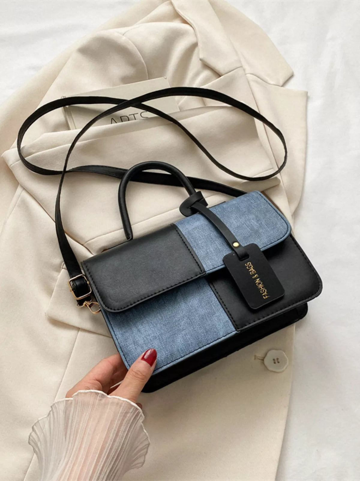 Chic two-tone PU leather crossbody bag in black and blue denim with a gold tag.