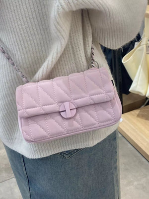Mini quilted flap chain bag in pink with a crossbody strap and round closure detail.