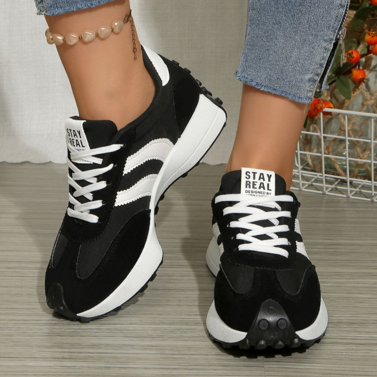 Black and white lace up round toe sneakers with chunky sole and "STAY REAL" detail.
